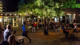 People eating and drinking in outdoor courtyard on summer evening
