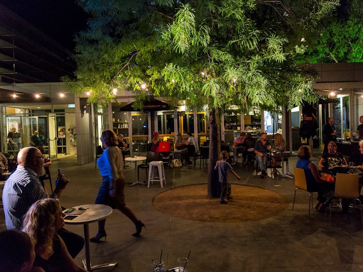 People eating and drinking in outdoor courtyard on summer evening