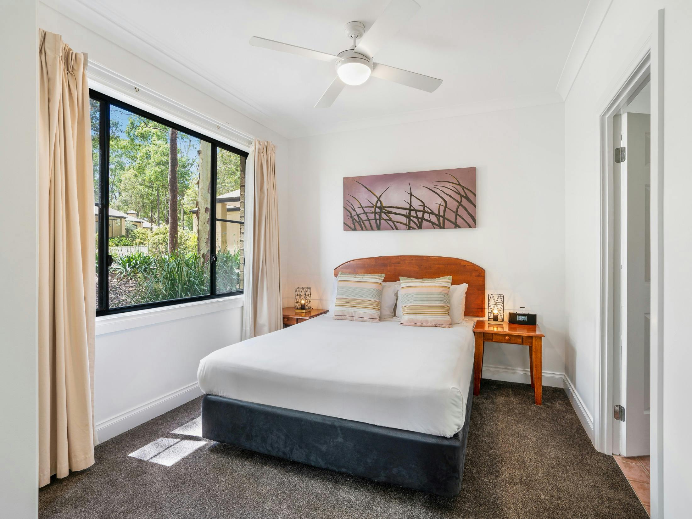 Bright bedroom with queen bed, bedside tables and large window