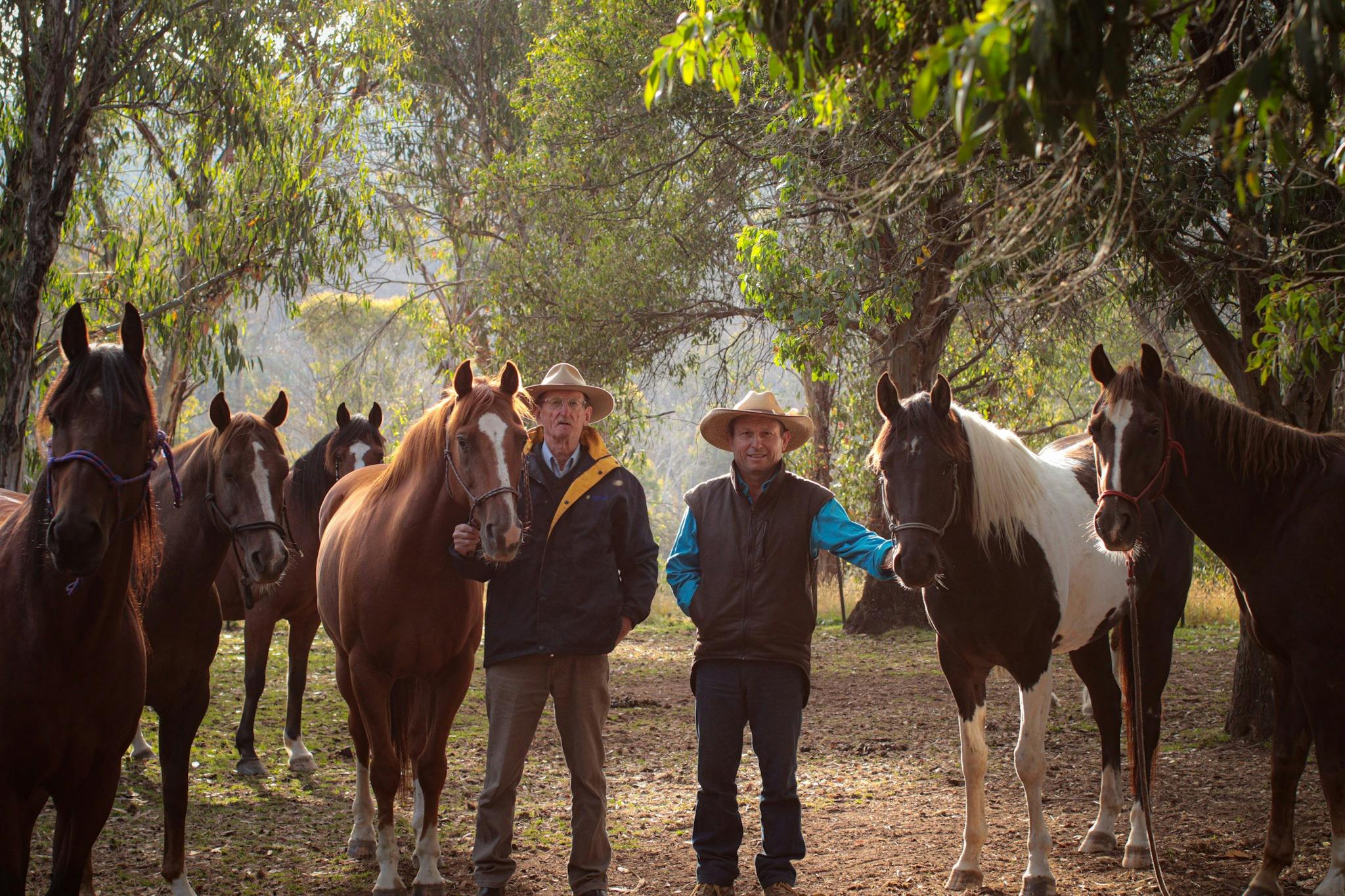 Two men standing with horses