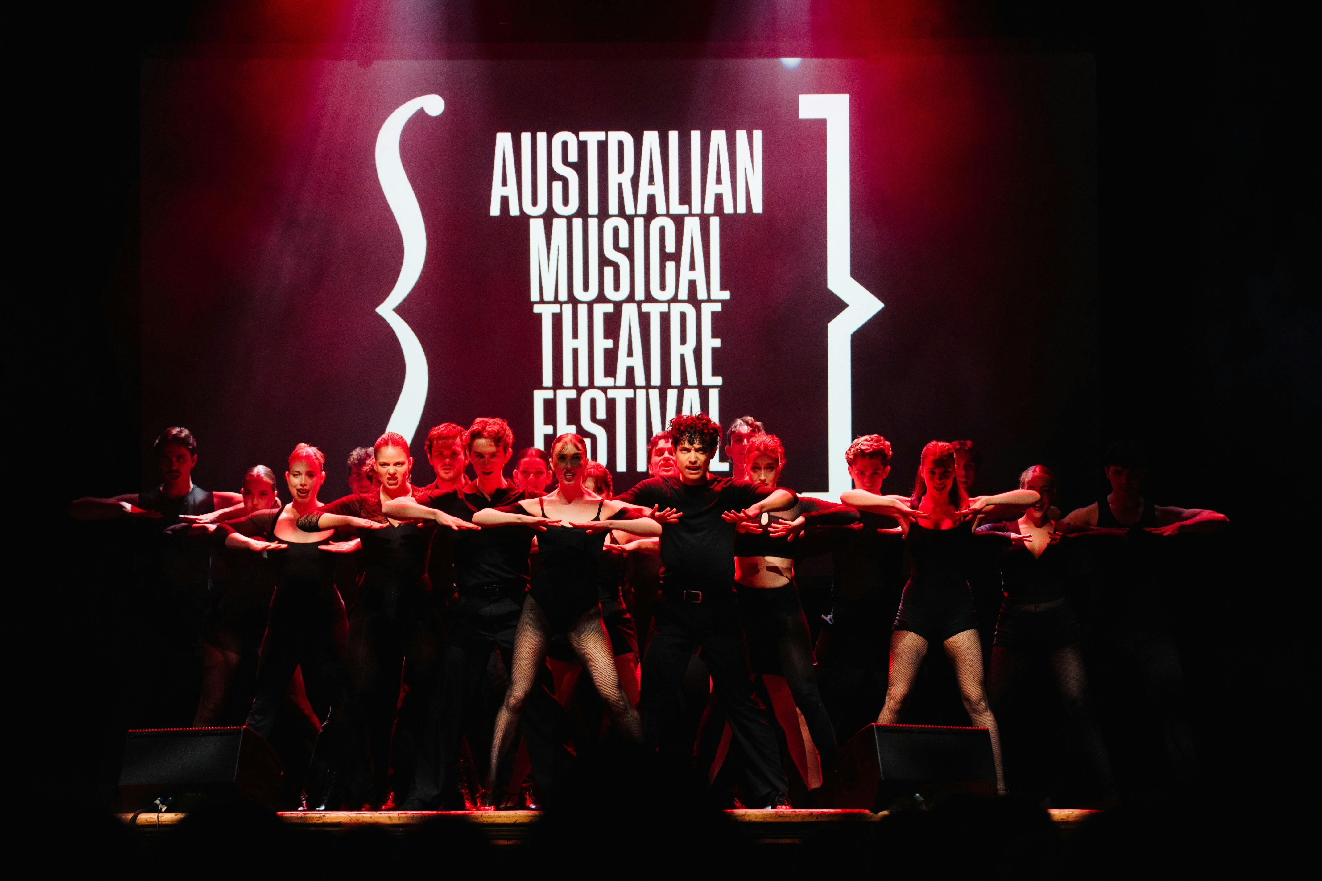 Performers dancing on stage in front of a projection of the festival logo