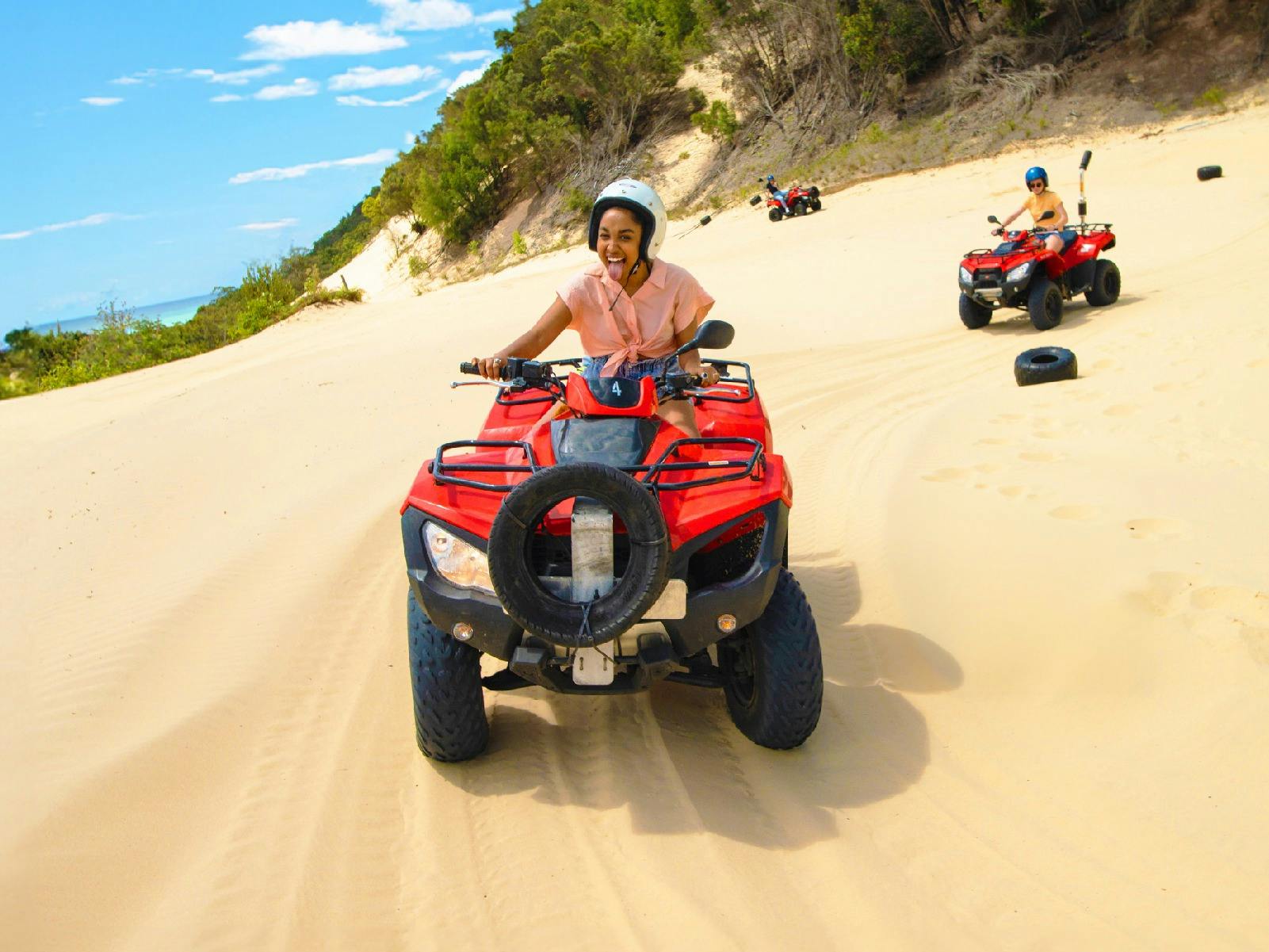 Women riding an ATV Quad Bike through the sand dunes