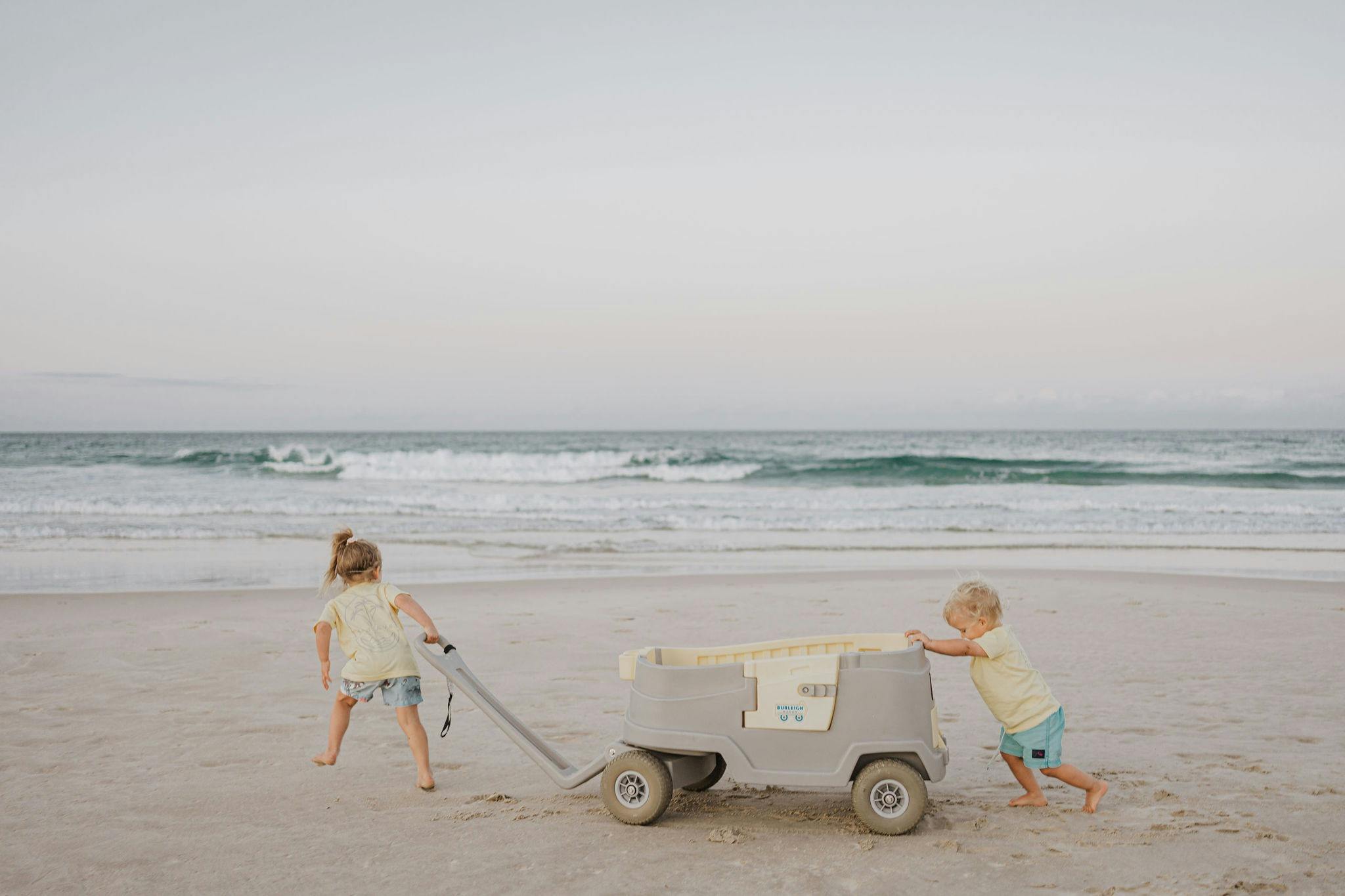 Children on beach pushing a beach wagon