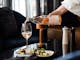 Waiter pouring glass of rose wine to accompany an entree in a moody lounge area at the Gateway