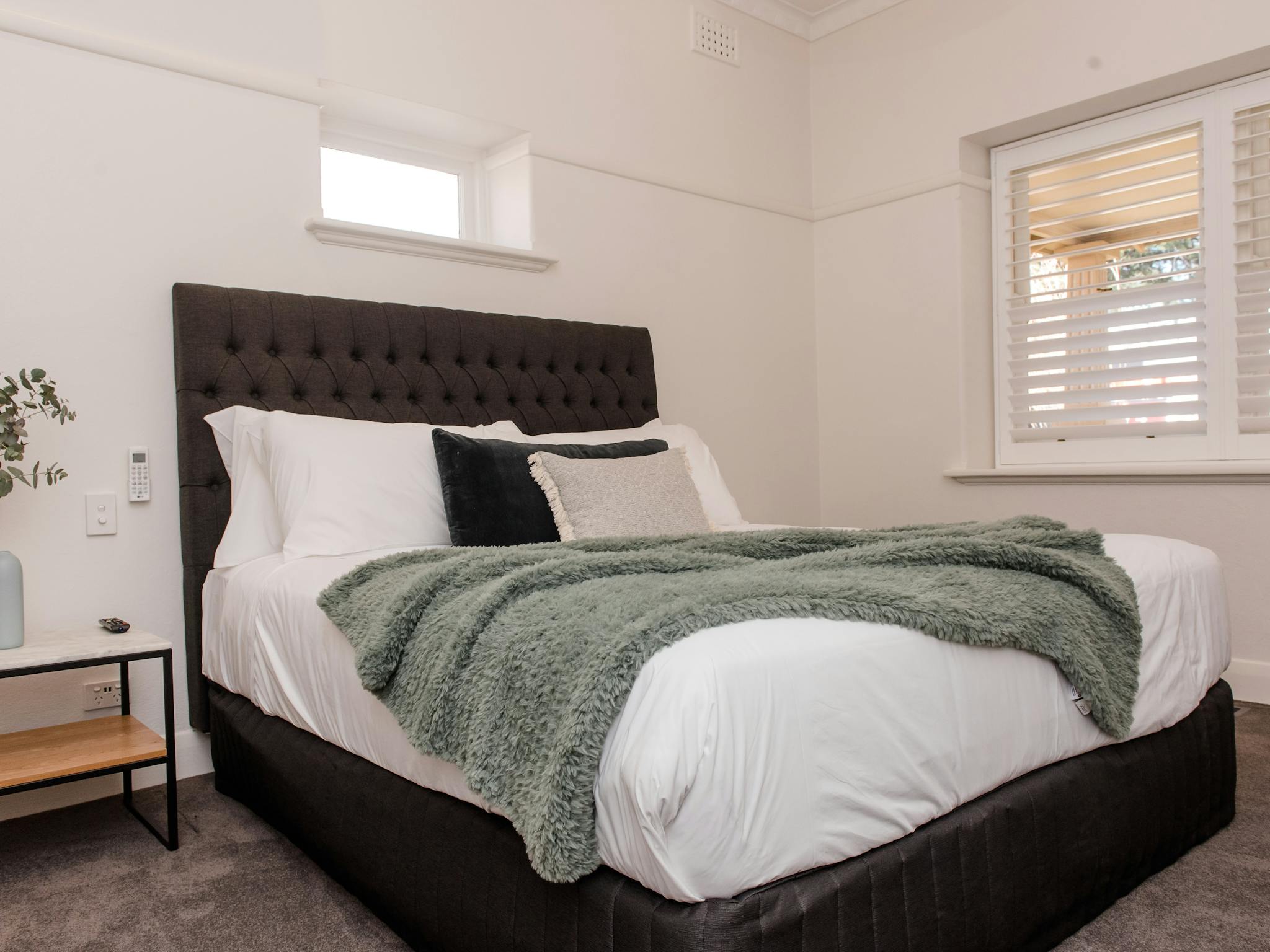 Self contained townhouse bedroom showing comfortable new bed, bedside table and window to verandah