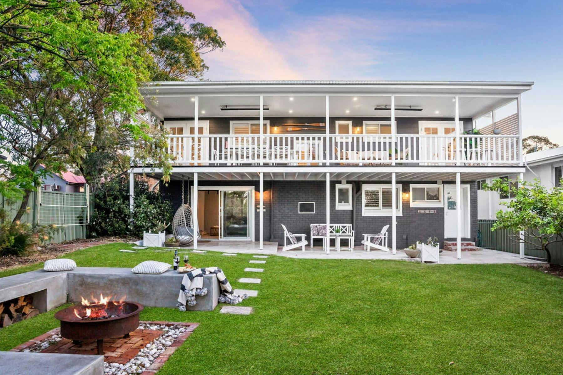 건물 뒤편의 이미지입니다. 뒷마당에서 화덕이 타고 있습니다. 야외 가구가 깔끔하게 배치되어 있습니다.