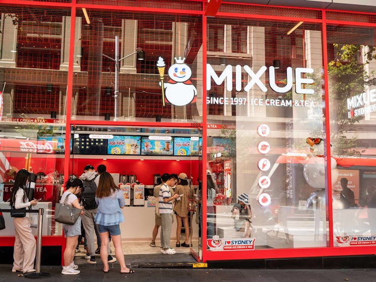 Photo of Mixue shopfront with people lining up and ordering tea and icecream