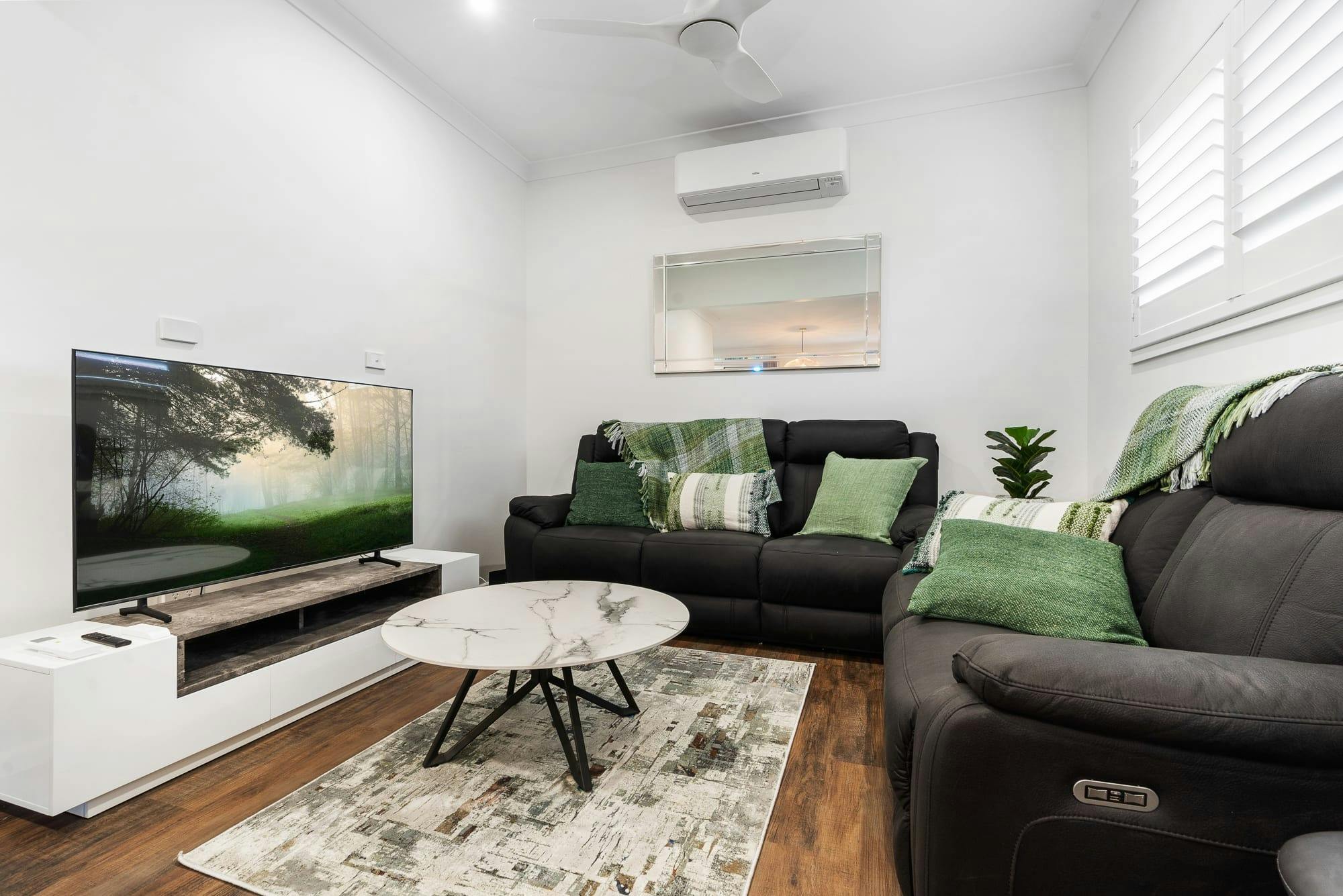 2 black couches with a rug, coffee table and tv on entertainment unit