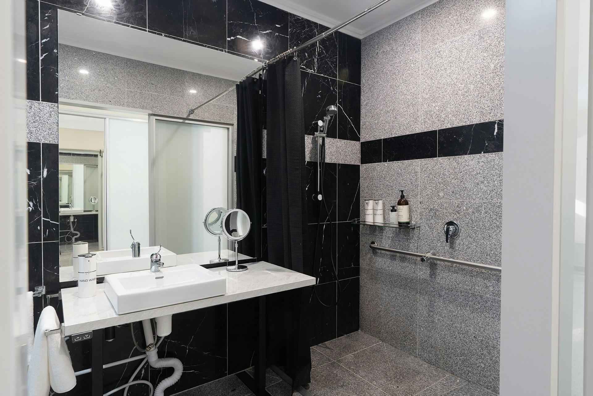 Roll in shower with adjustable height vanity and handrails in shower and around toilet