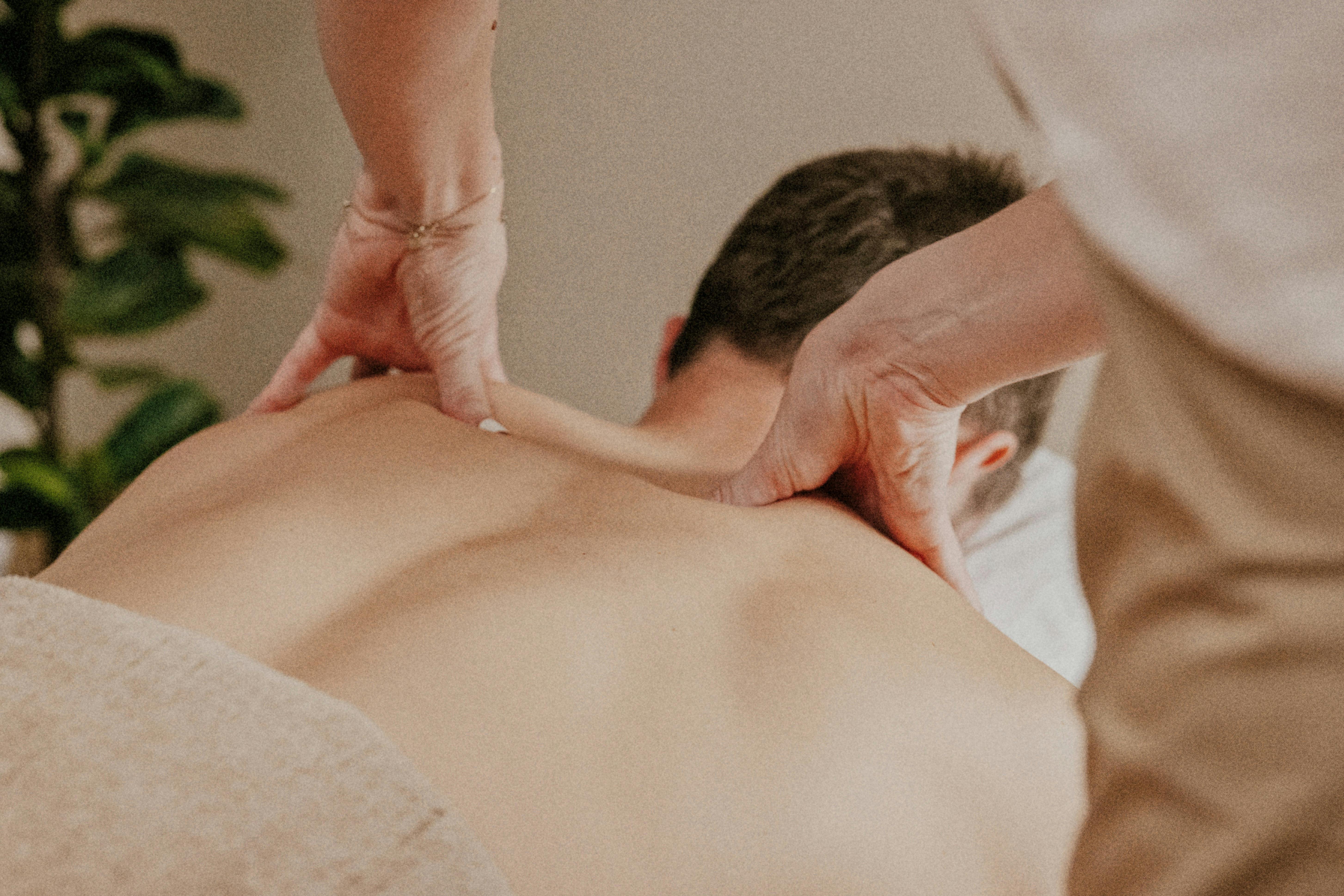 A man lying on his front, receiving a gentle massage