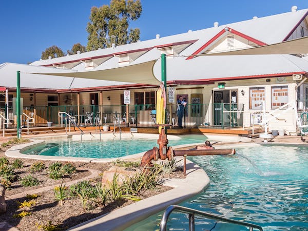 A large pool with cloth shade covers, a building in the background A large pool with cloth shade covers, a building in the background