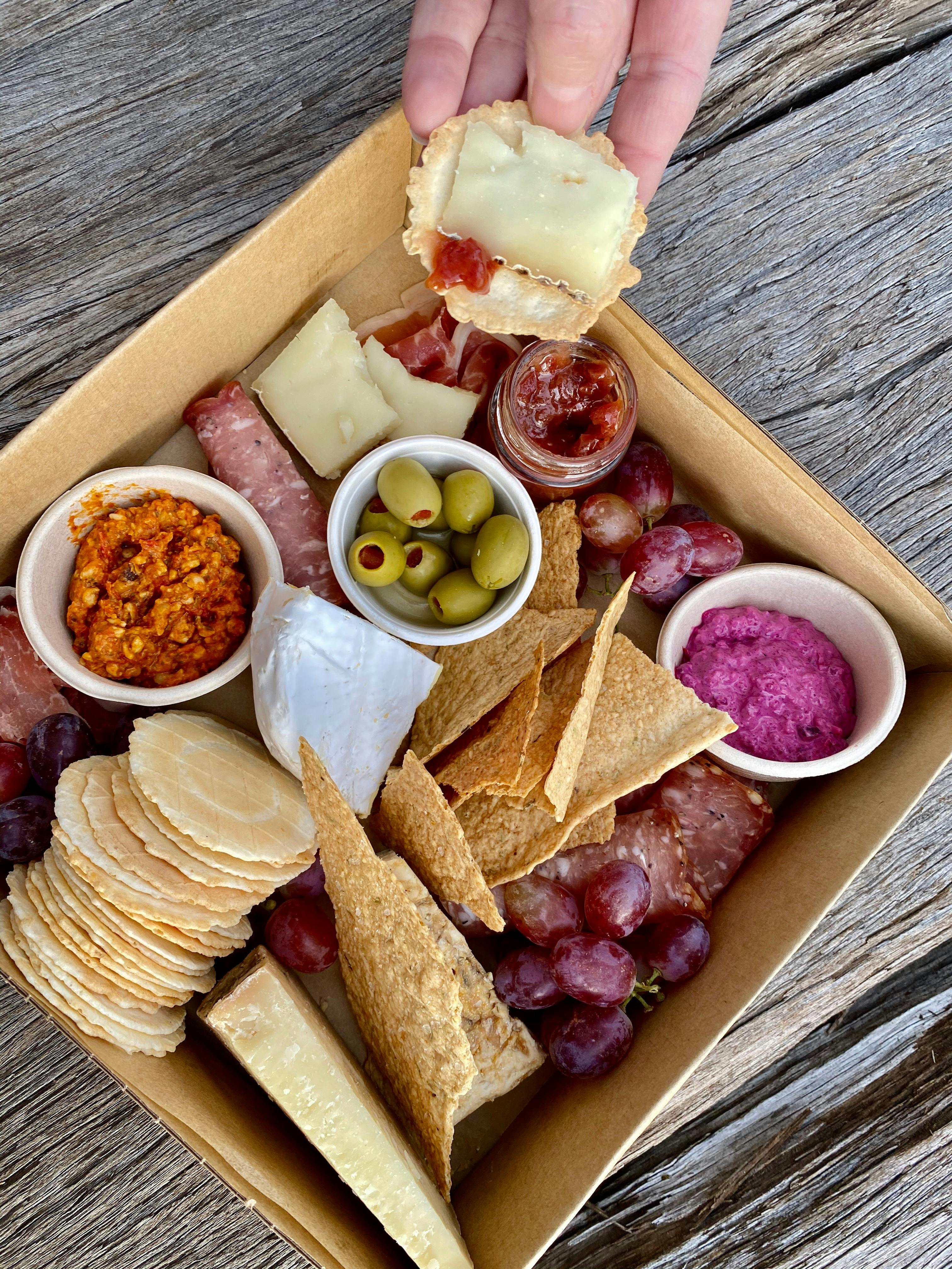 Grazing box full of savoury treats, like meats, cheeses and dips, made ready to go to enjoy anywhere