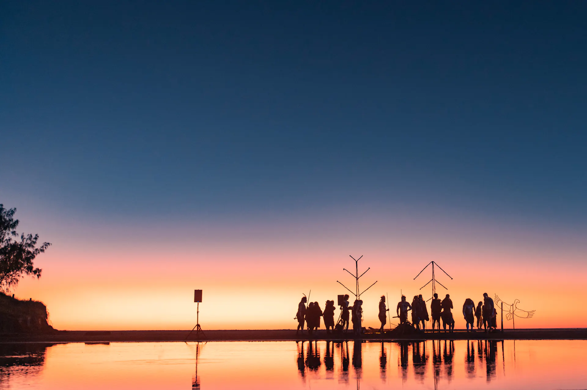 Performers gathered on a beach at dawn