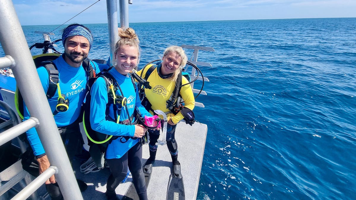 Three divers are geared on a boat ready to jump into the water