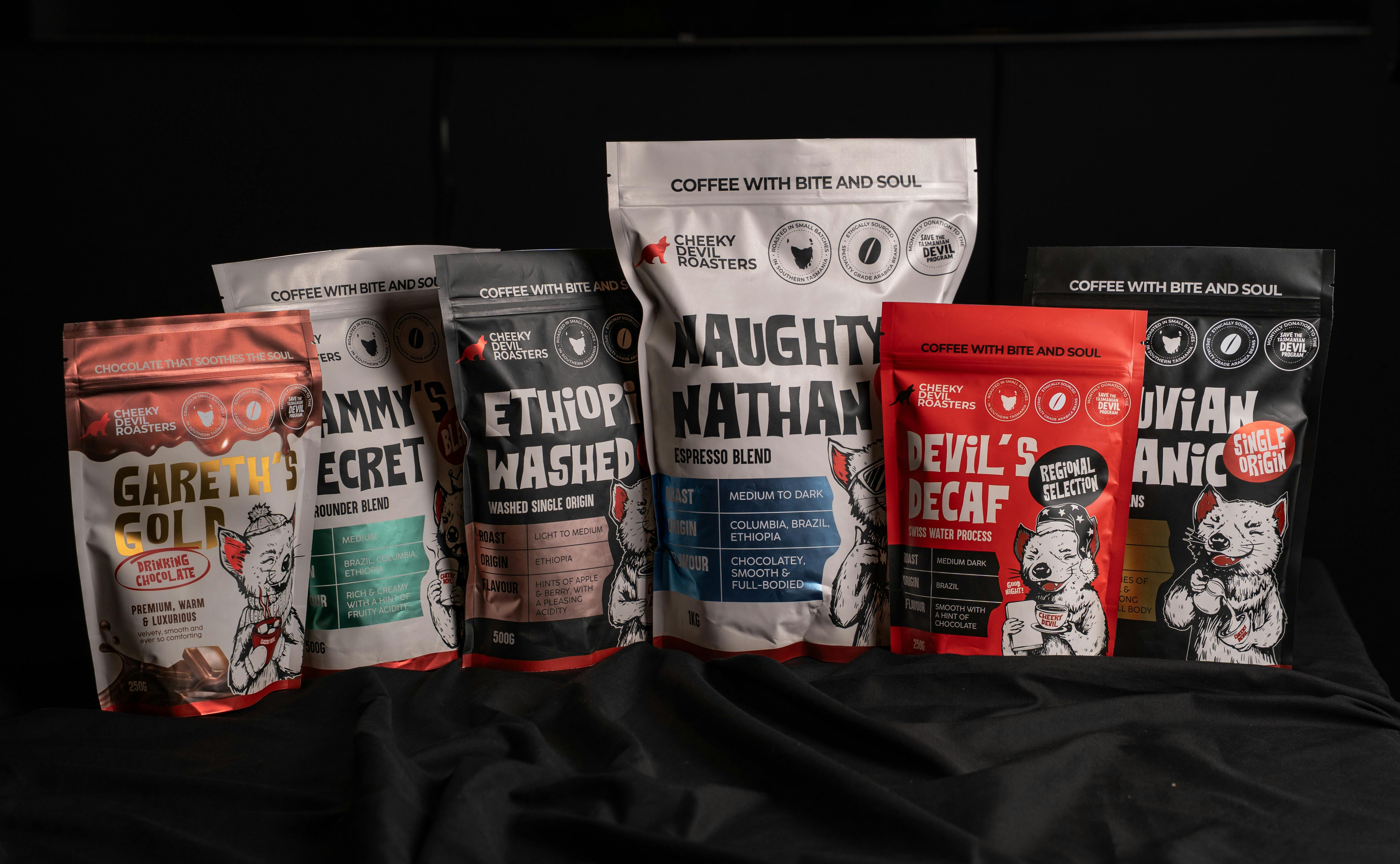 Bags of Cheeky Devil specialty coffee and drinking chocolate displayed together.