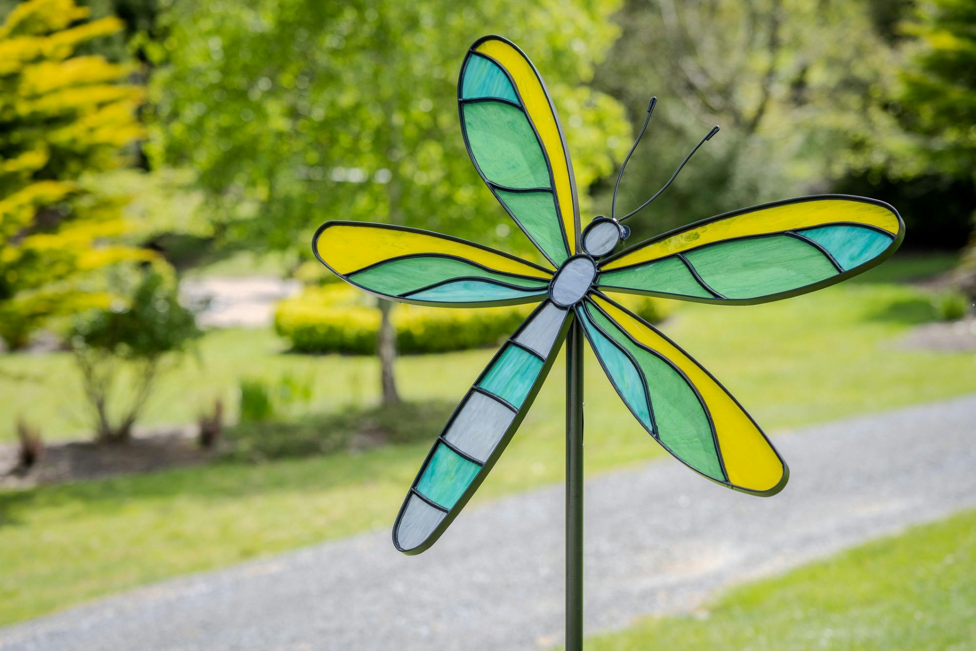 Stained glass dragonfly sculpture mounted on a steel stem.