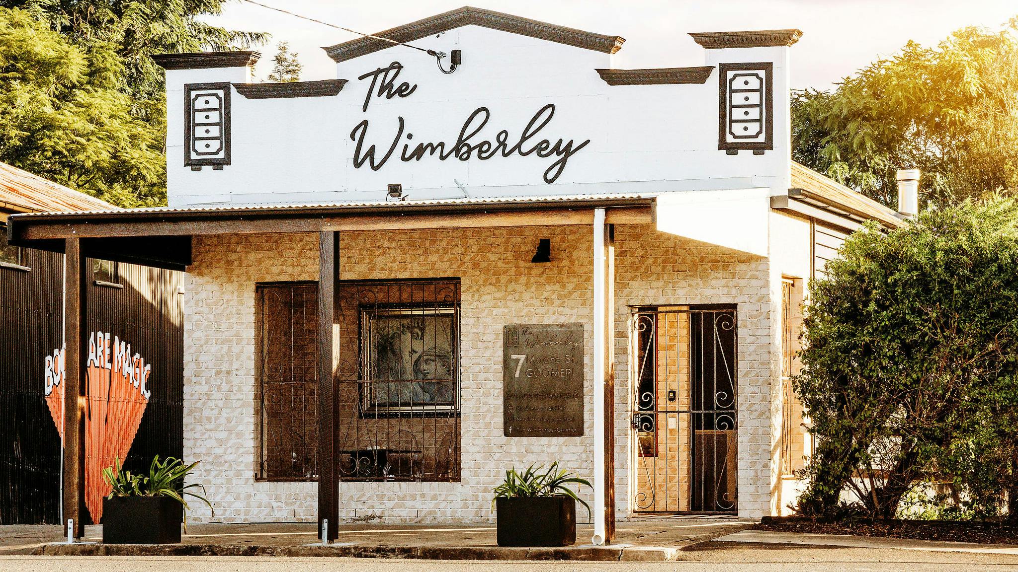 Street View and facade of brick building with decorative parapet and signage reading The Wimberley Street View and facade of brick building with decorative parapet and signage reading The Wimberley
