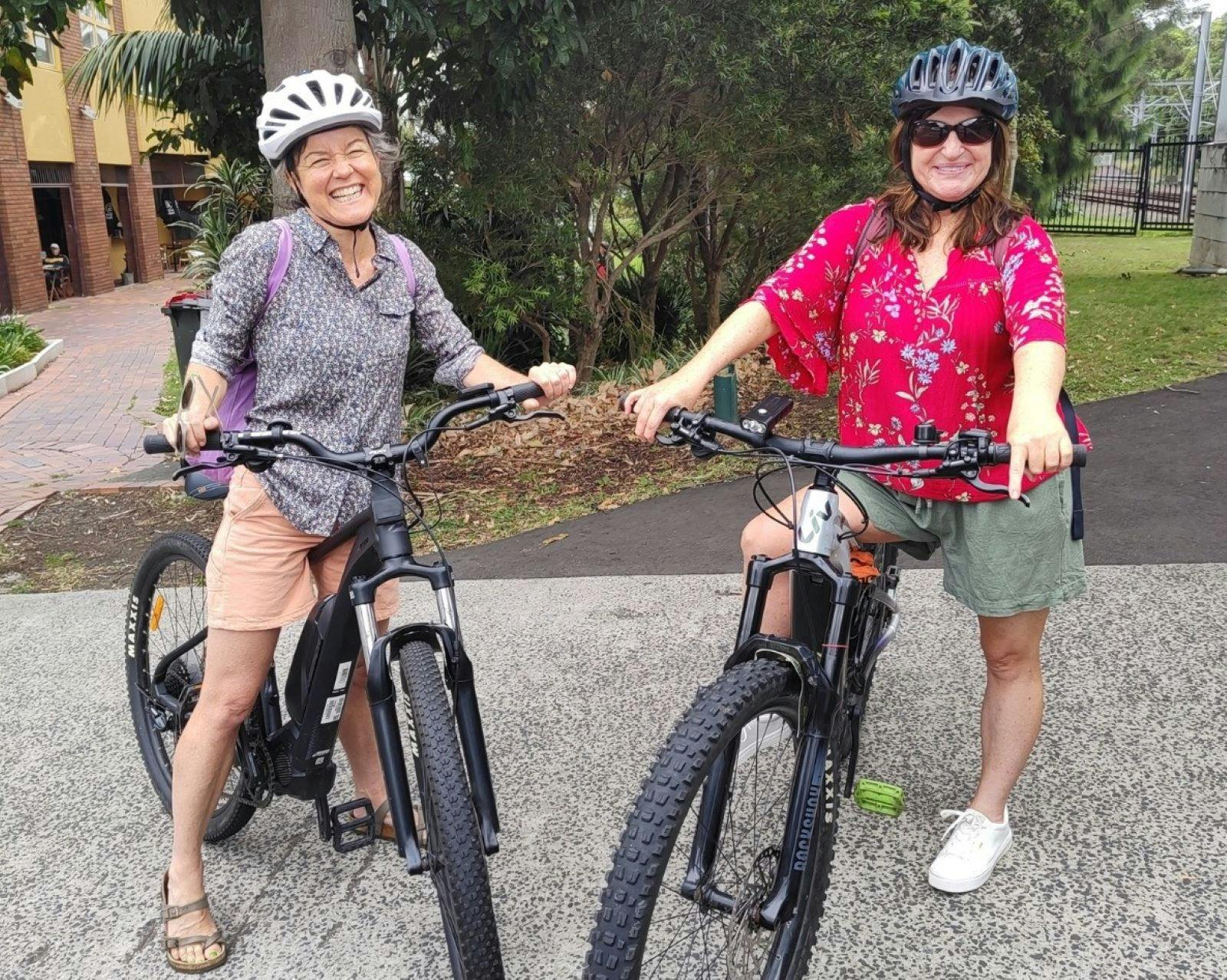 Two female customers with huge smiles, helmets on ready to set off on their ebikes