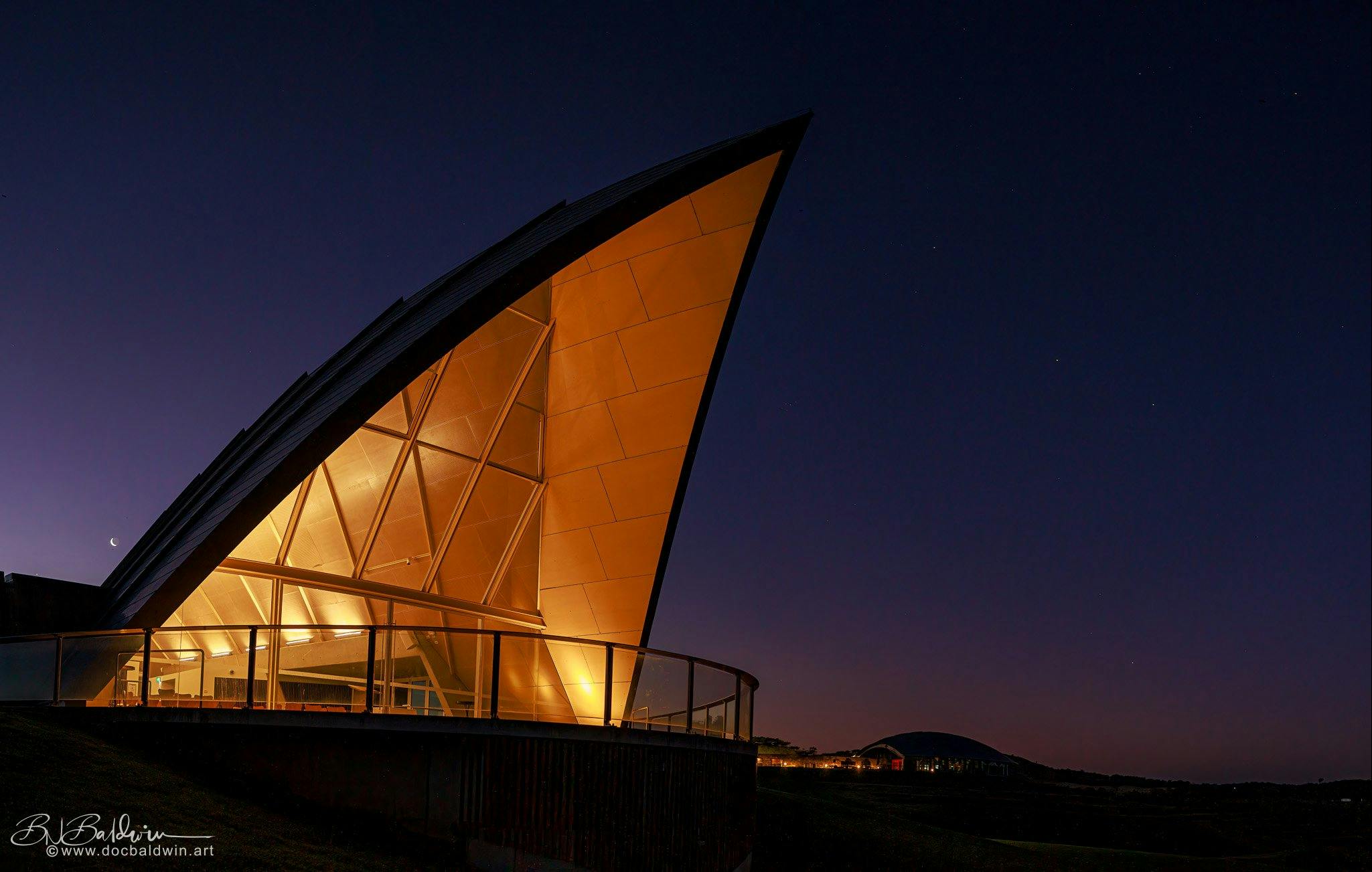 The triangular roof of the Margaret Whitlam Pavilion lights up against an evening sky