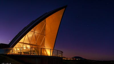 The triangular roof of the Margaret Whitlam Pavilion lights up against an evening sky