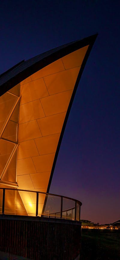 The triangular roof of the Margaret Whitlam Pavilion lights up against an evening sky