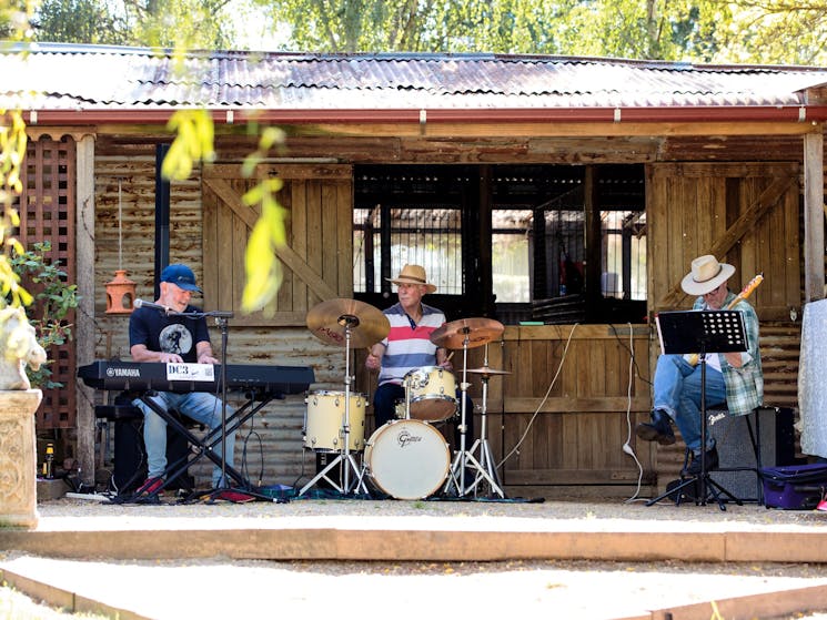 three musicians playing on the verandah of a timber cottagge