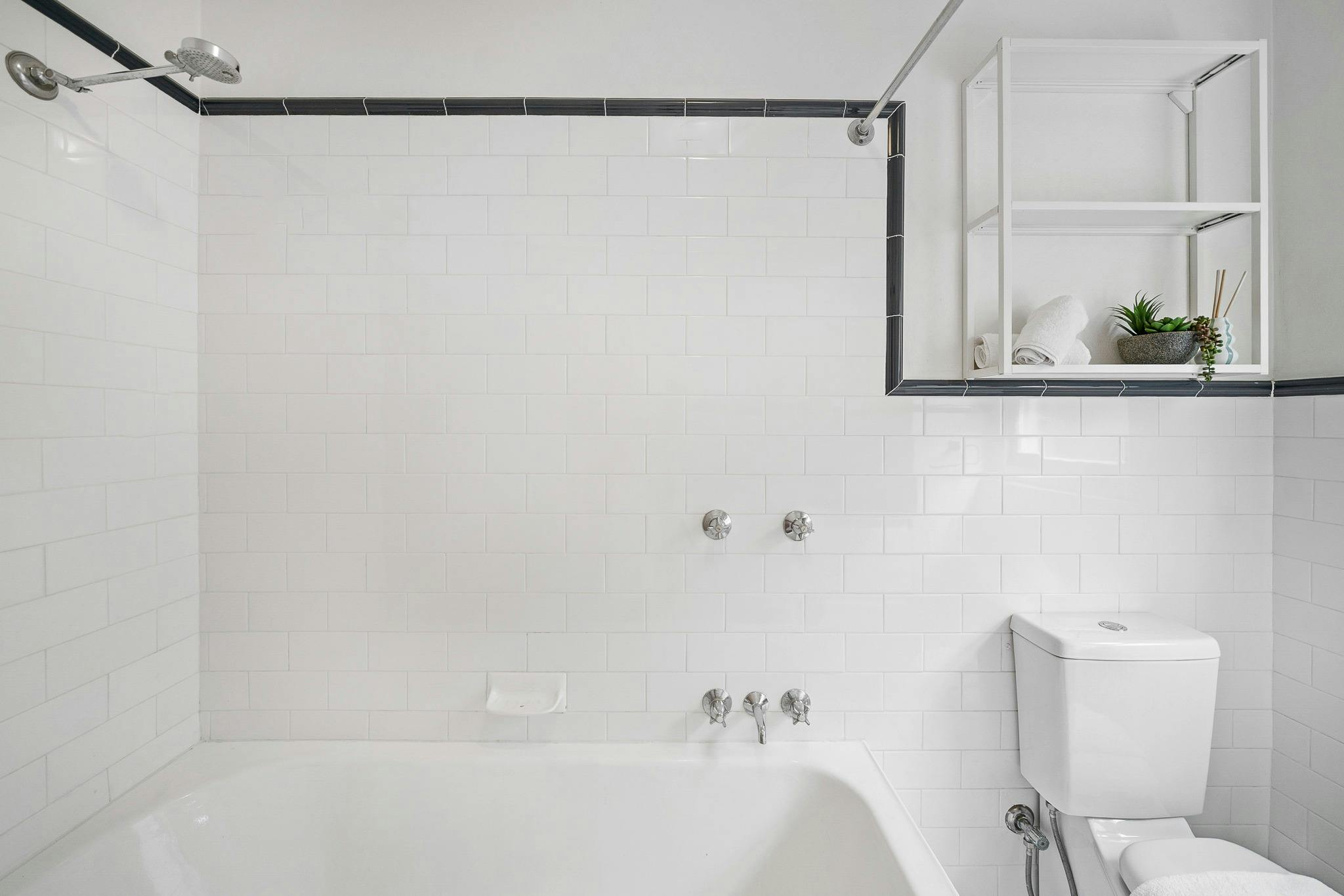 乾淨、清新的浴室配有白色瓷磚和浴缸，為您帶來極致舒適。