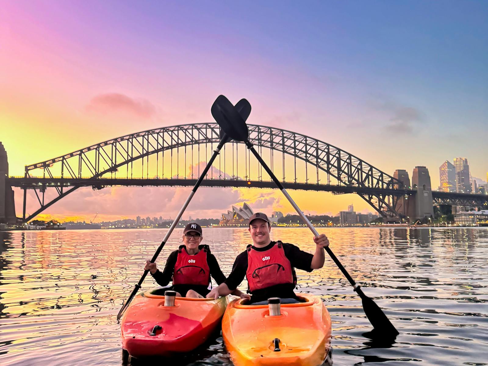 Two kayakers with Sydney Harbour Bridge and Sydney Opera House in the background on Sydney Harbour