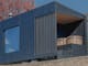 Large charred wood sauna in nature with cedar cold plunge tubs on deck and large sauna window