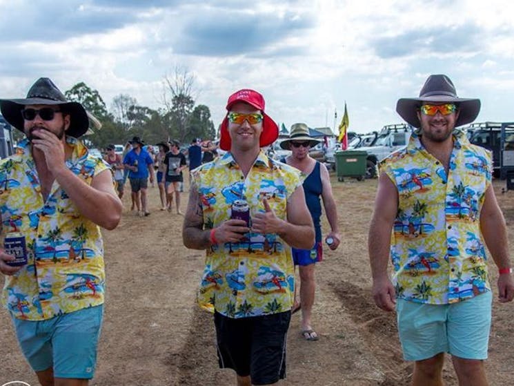 Three young men dressed in sleeveless colorful shirts as they head to the event.