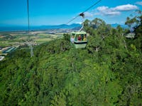 Skyrail gondola over rainforest with 3 people and blue sky