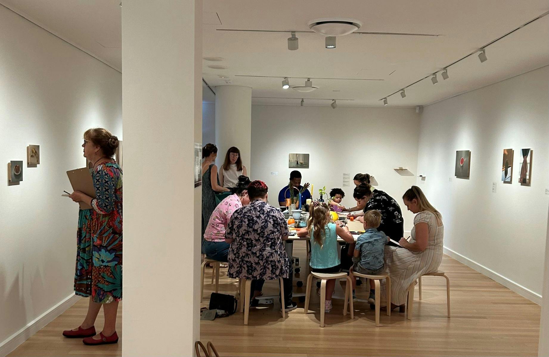 group of people sit at a table doing crafts