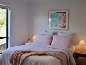 Queen bedroom with soft linen bedding, bedside lamps and coastal artwork at Harolds on the Hill