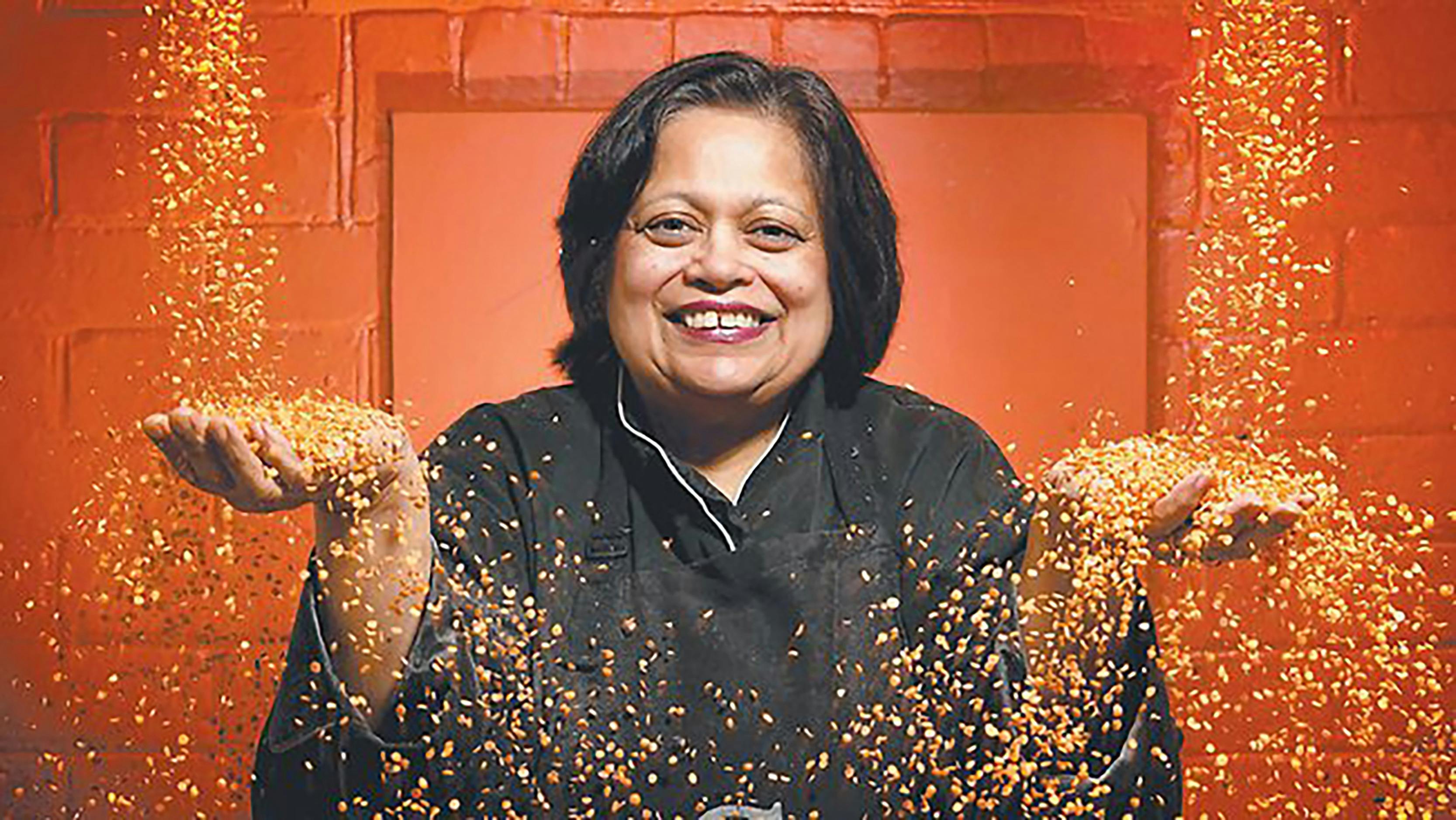 Indian woman against red background with spices flowing in to her hands