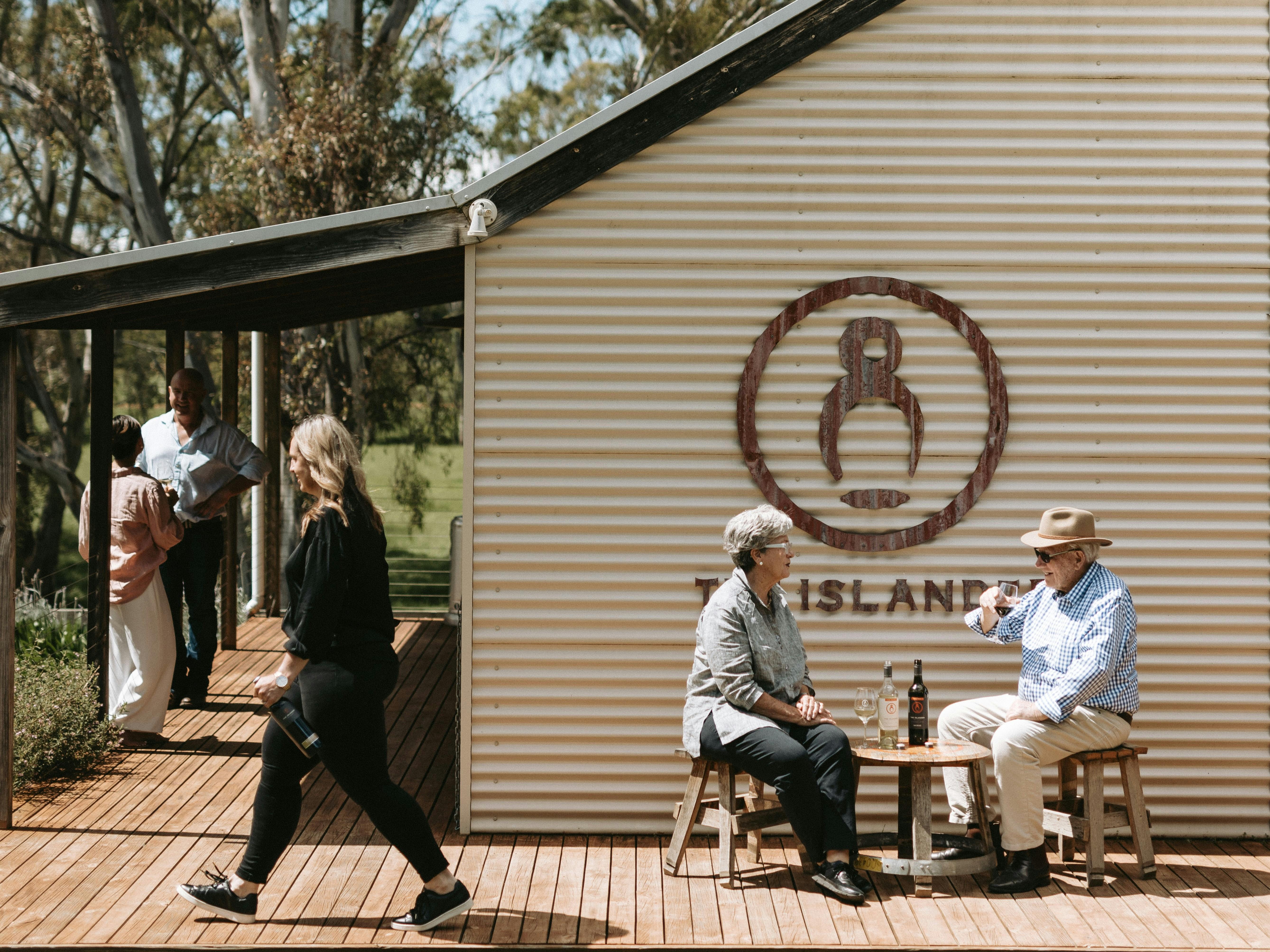 Two couples enjoying wine on the deck of The Islander Estate Vineayards tasting room