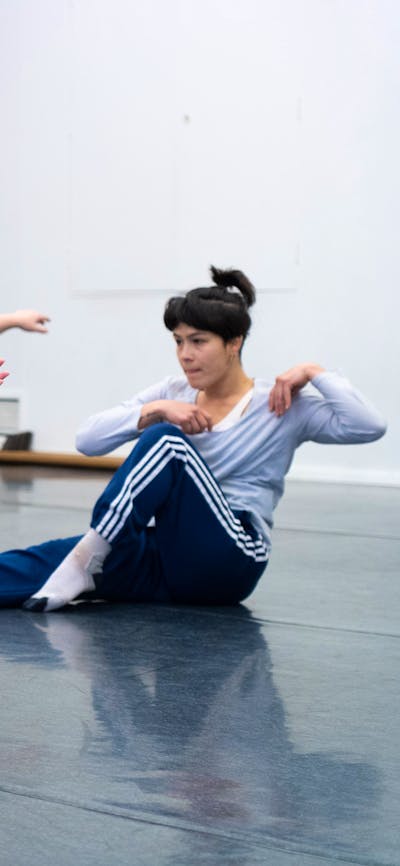 4 dancers are in the middle of twisting towards the camera. They are seated on the floor