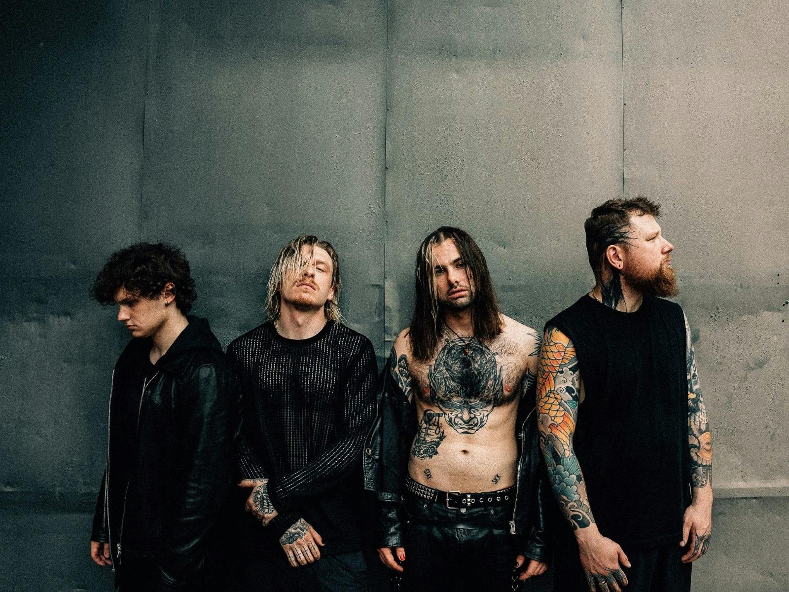 The four band members of Paleface Swiss against a wall looking to the side and to the camera
