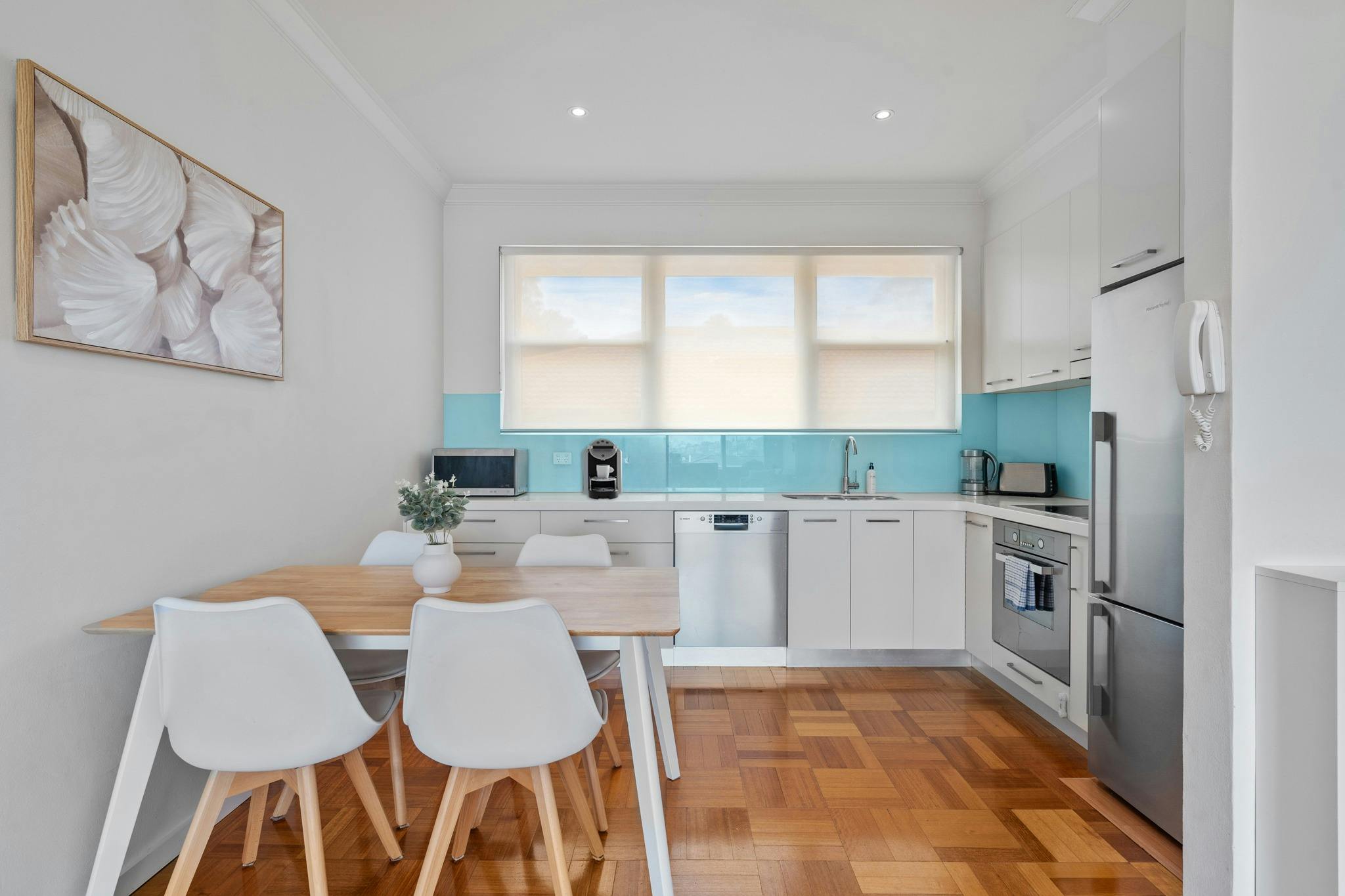 現代廚房配有白色櫥櫃和藍色後擋板，設備齊全。