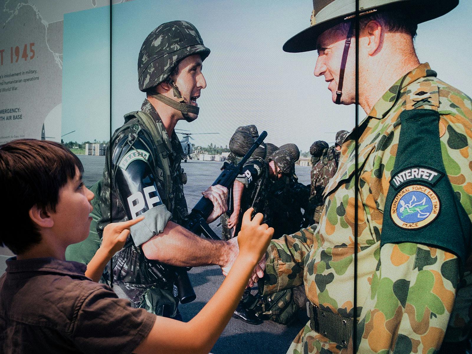 Young boy using the interactive screens inside Anzac Square Memorial Galleries
