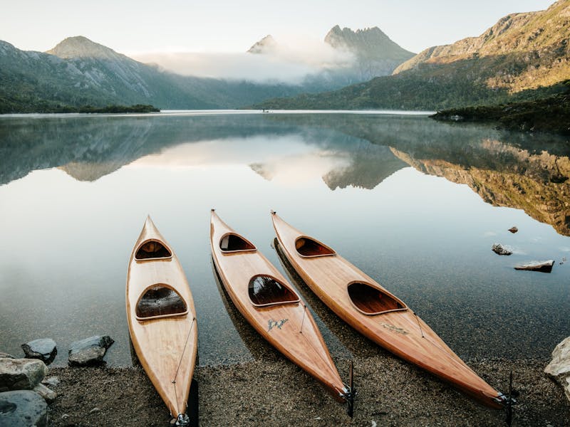 Three wooden kayaks lined up on the edge of Dove Lake
