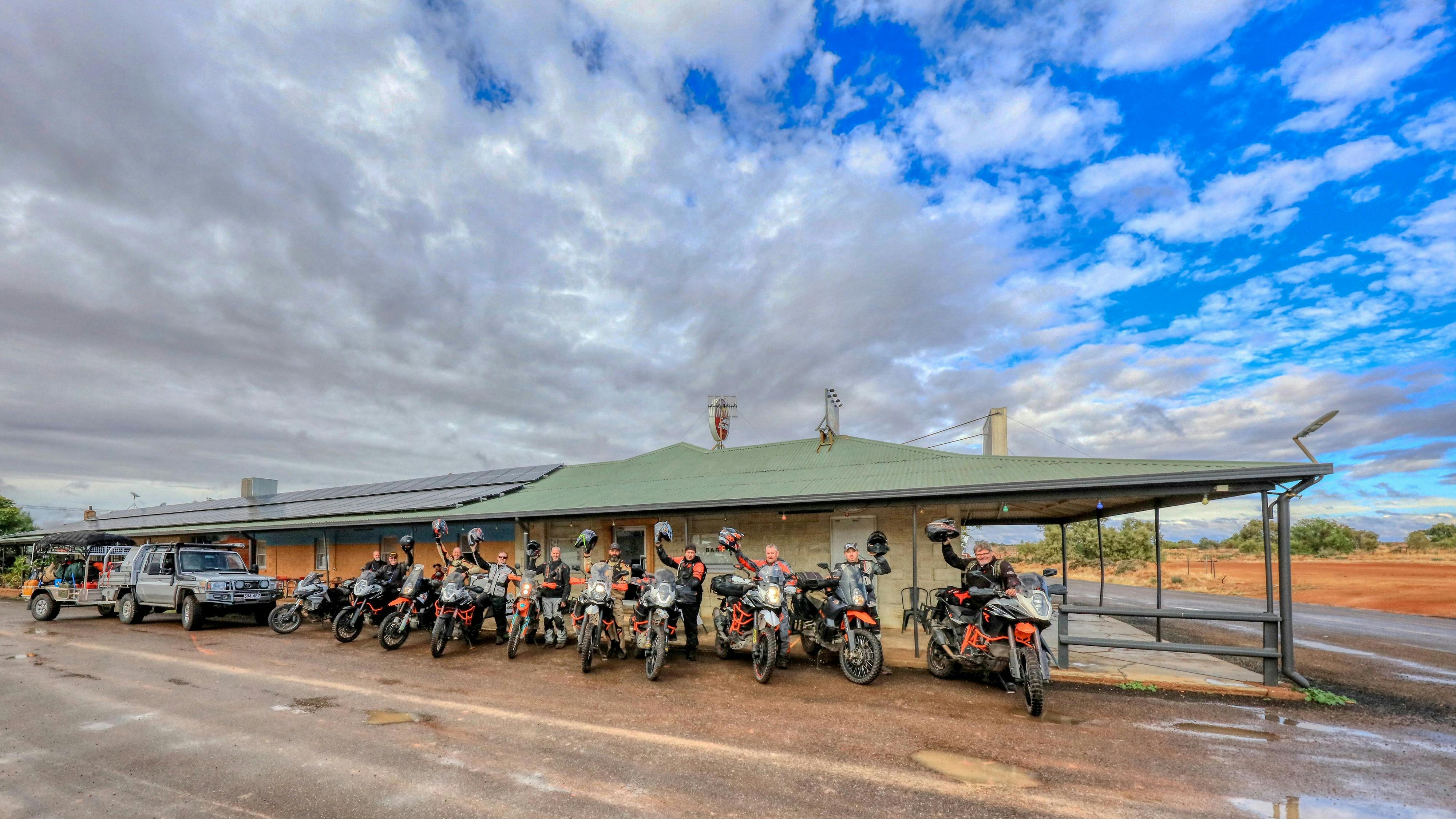 Motor bike riders out the front of the pub holding their helmets giving a happy wave