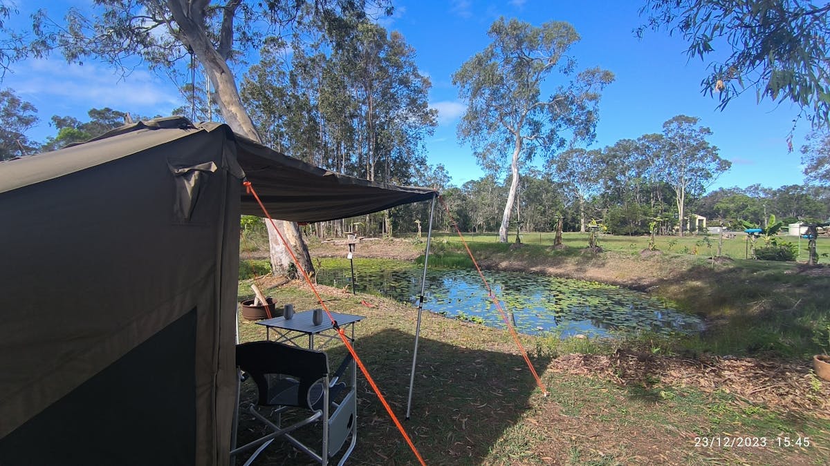 Luxury tent set, table and chairs looking out on to the Dam with lillies on it and gumtrees beyond