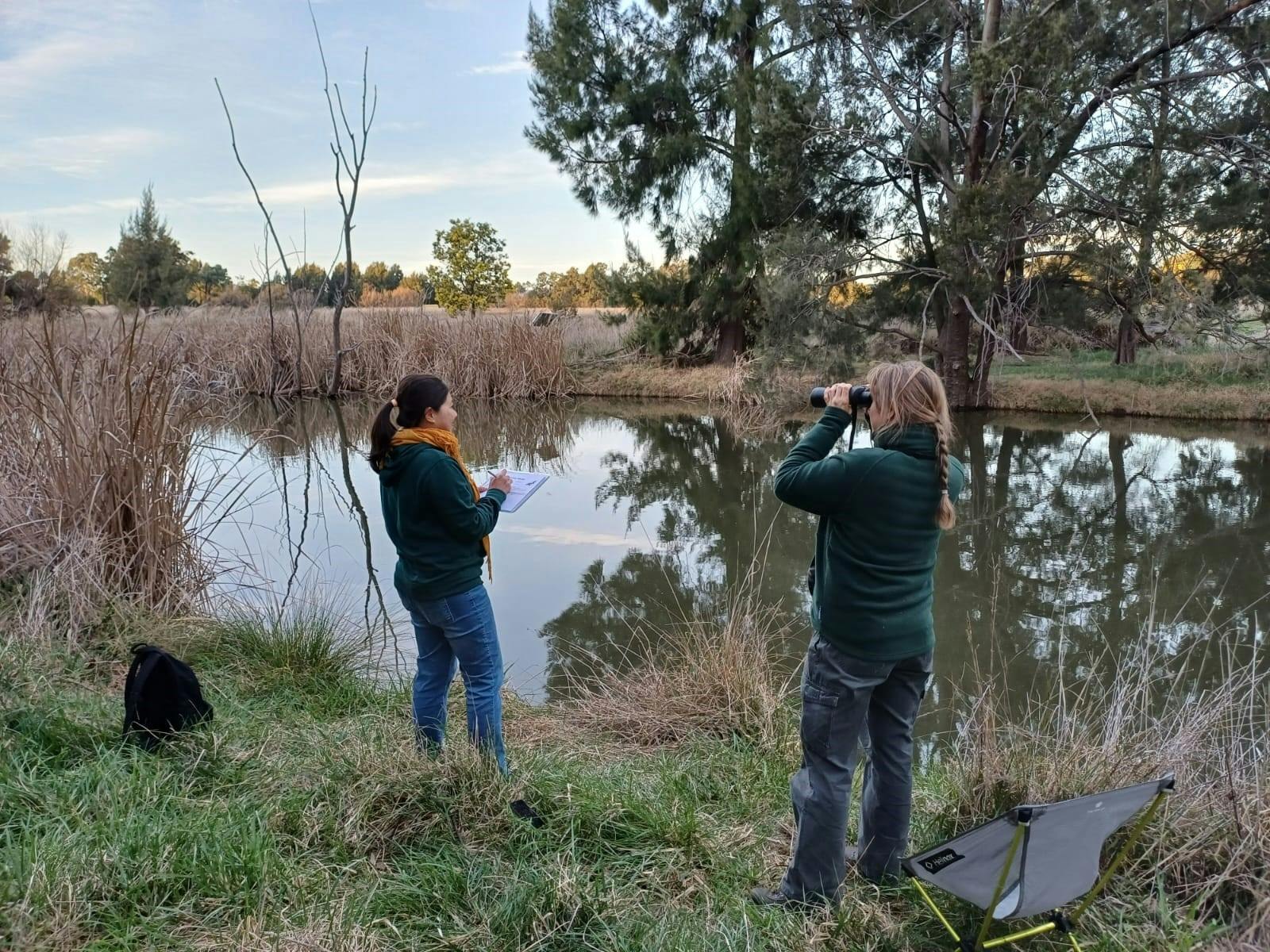 two people by a river looking for platypus