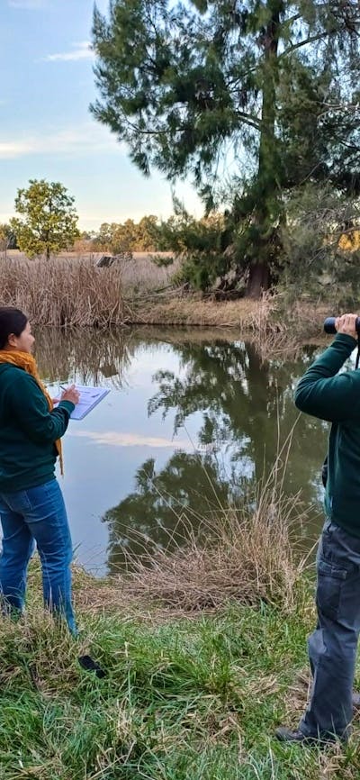 two people by a river looking for platypus