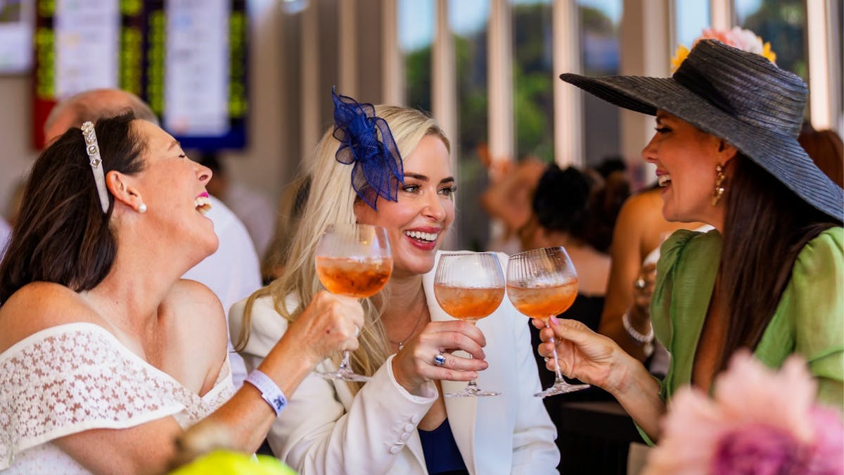 Three ladies laughing over drinks