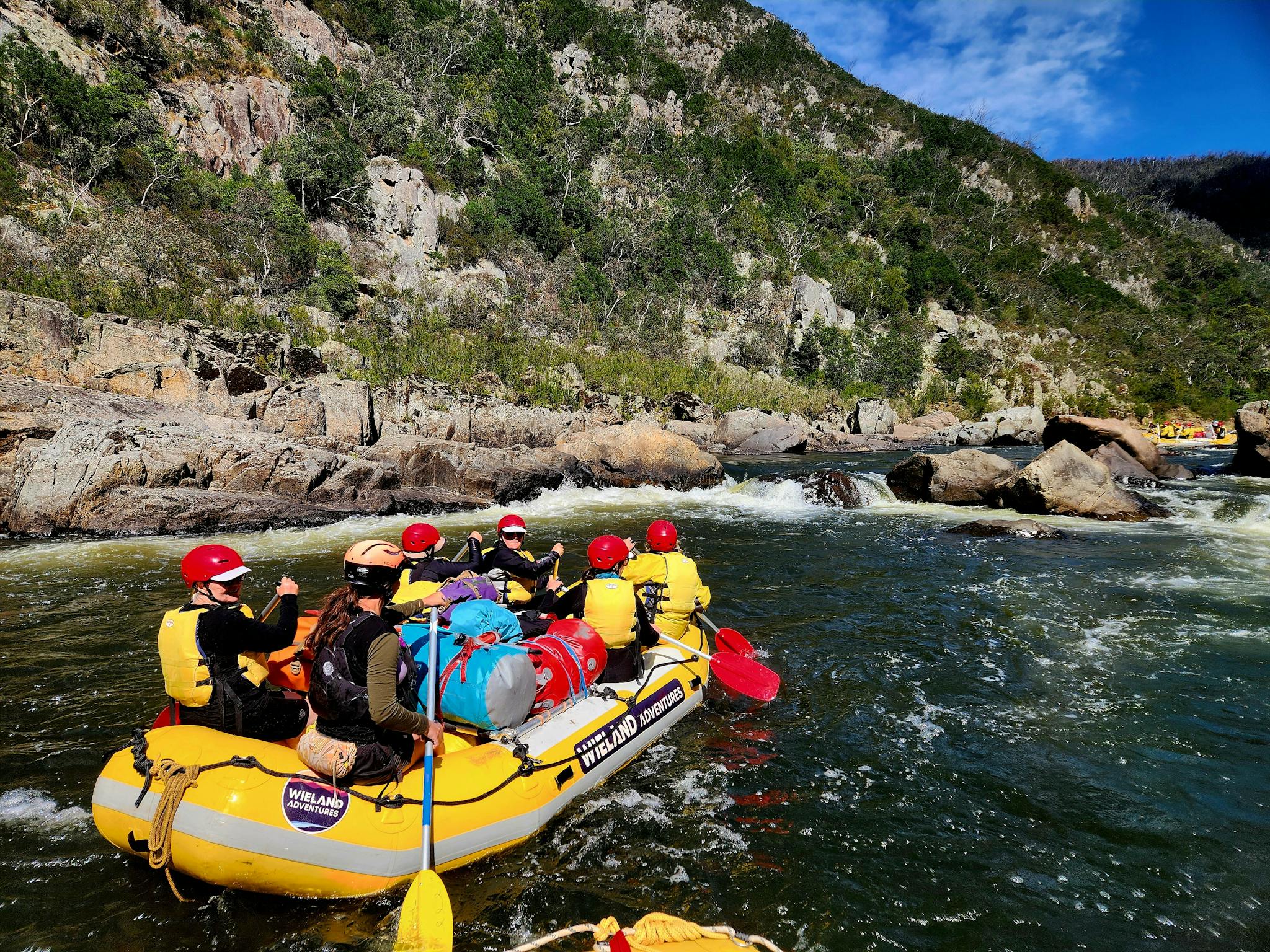 A sunny day on the Snowy River with a Wieland Adventures raft full of clients looking upstream.