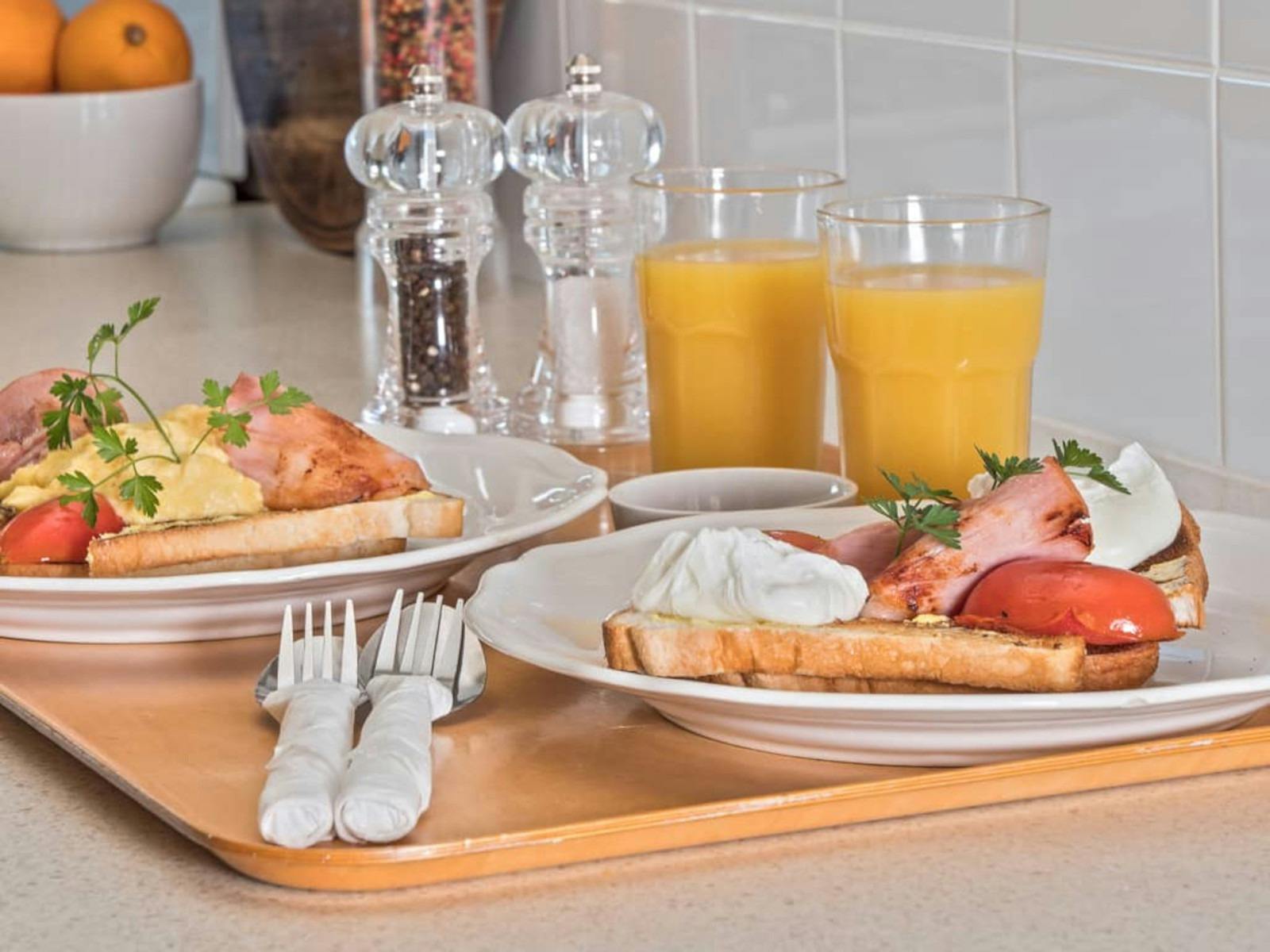 Bacon and eggs displayed beautifully on table with orange juice and salt and pepper
