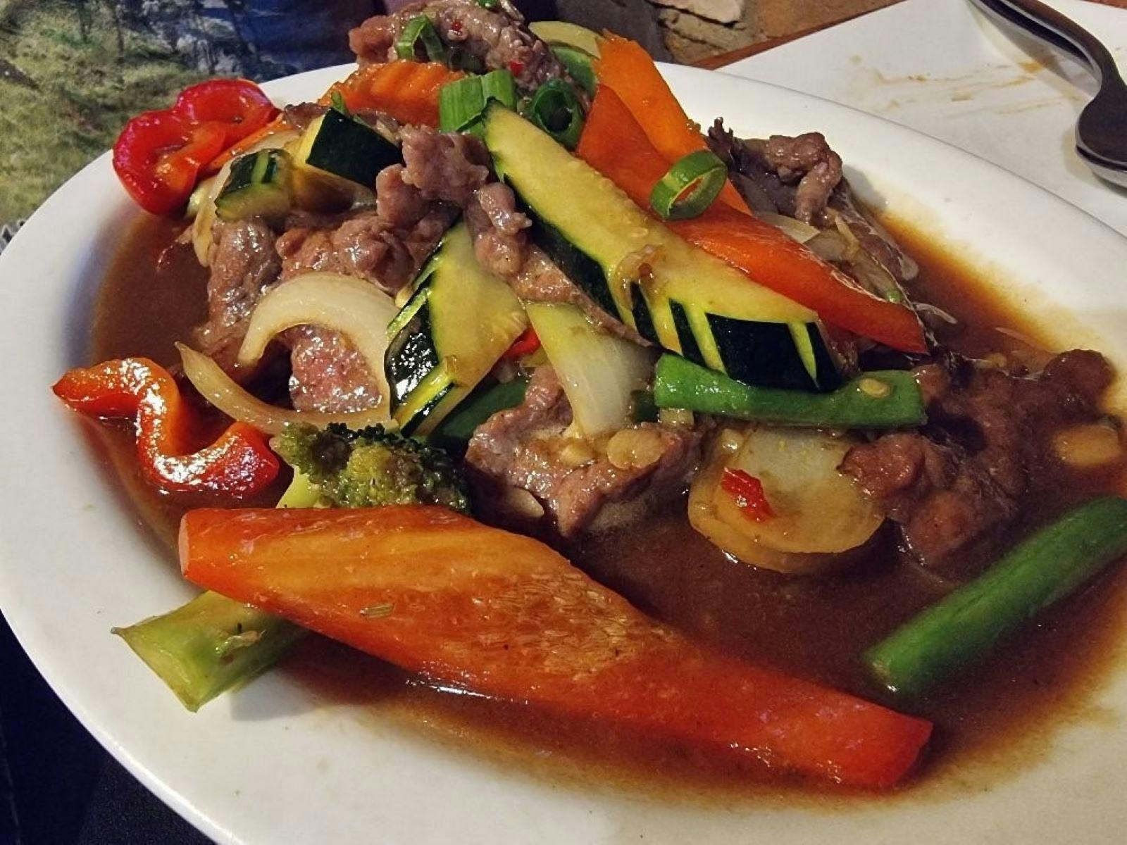 Thai meat and vegetable dish on white oval plate