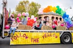 A group of children and adults on the back of a truck with the sign Follow the Yellow Brick Road.