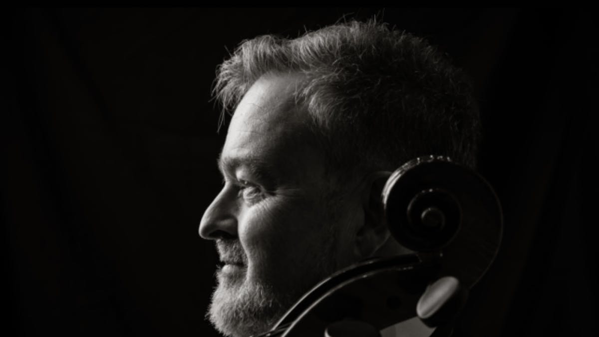 Black-and-white portrait of a cellist in profile, looking toward the light